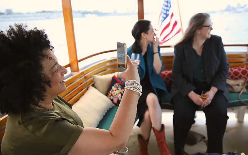 A woman taking a photo on a boat with two friends in the background