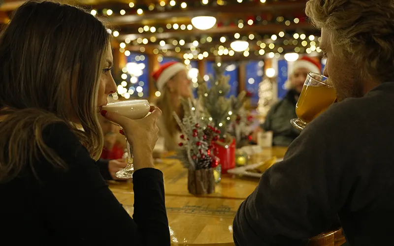 A couple enjoying cocktails with holiday decor in the background