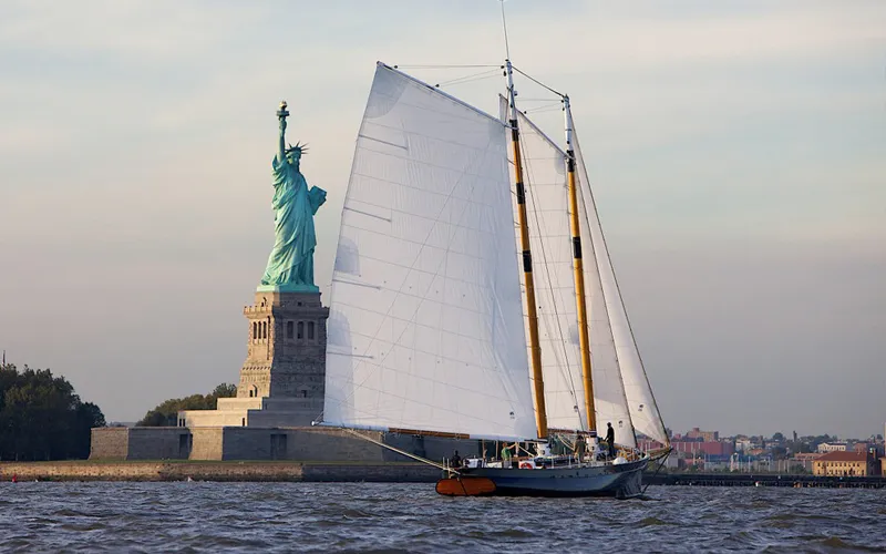 Schooner America 2.0 with the statue of liberty in the background