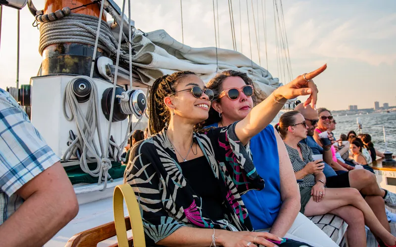 Guests on a schooner pointing out at something in the NY Harbor