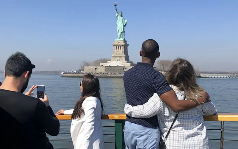 Guests looking out at the statue of liberty from the bow of a yacht